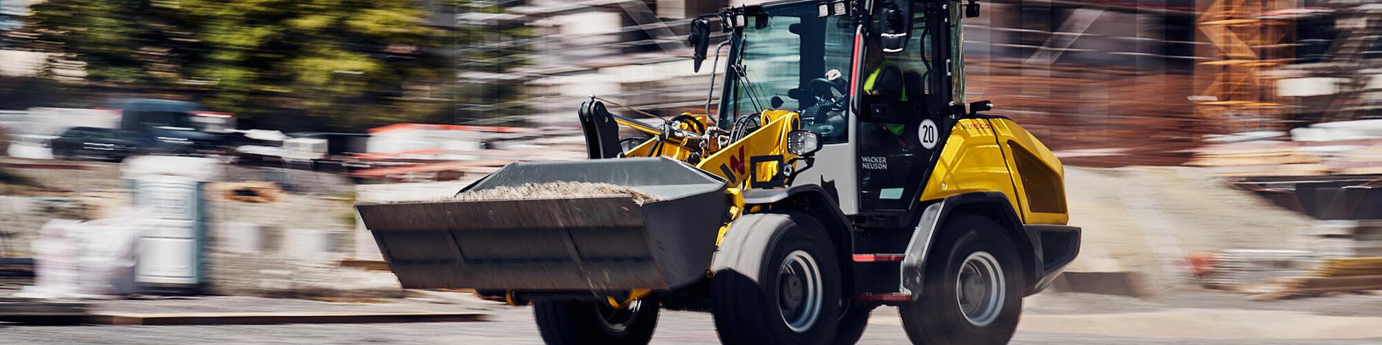 Wacker Neuson WL950p model yüksek performanslı tekerlekli yükleyici, bir şantiyede yüksek hızda ilerliyor.