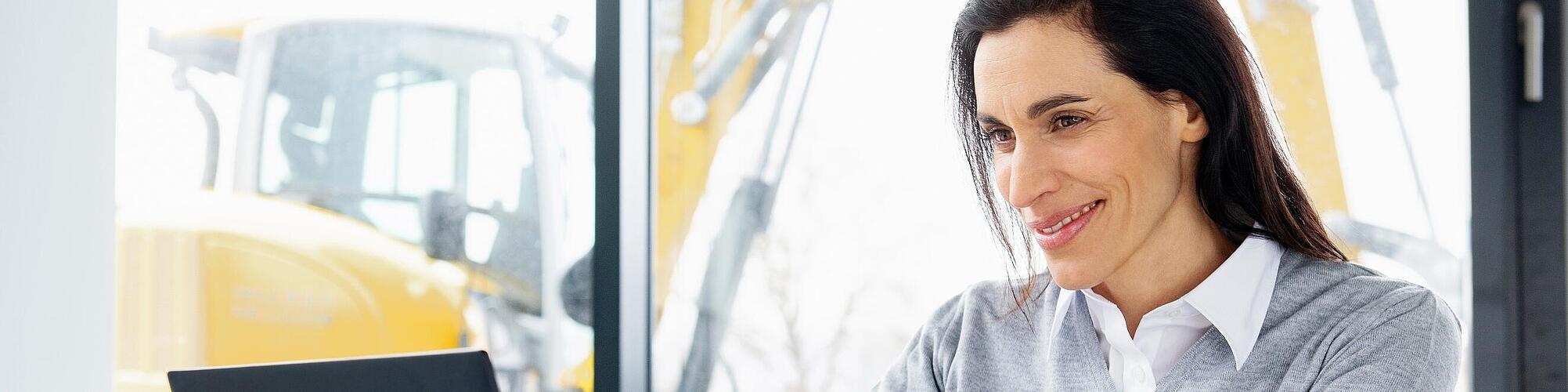 Wacker Neuson employee sitting at a laptop and smiling.