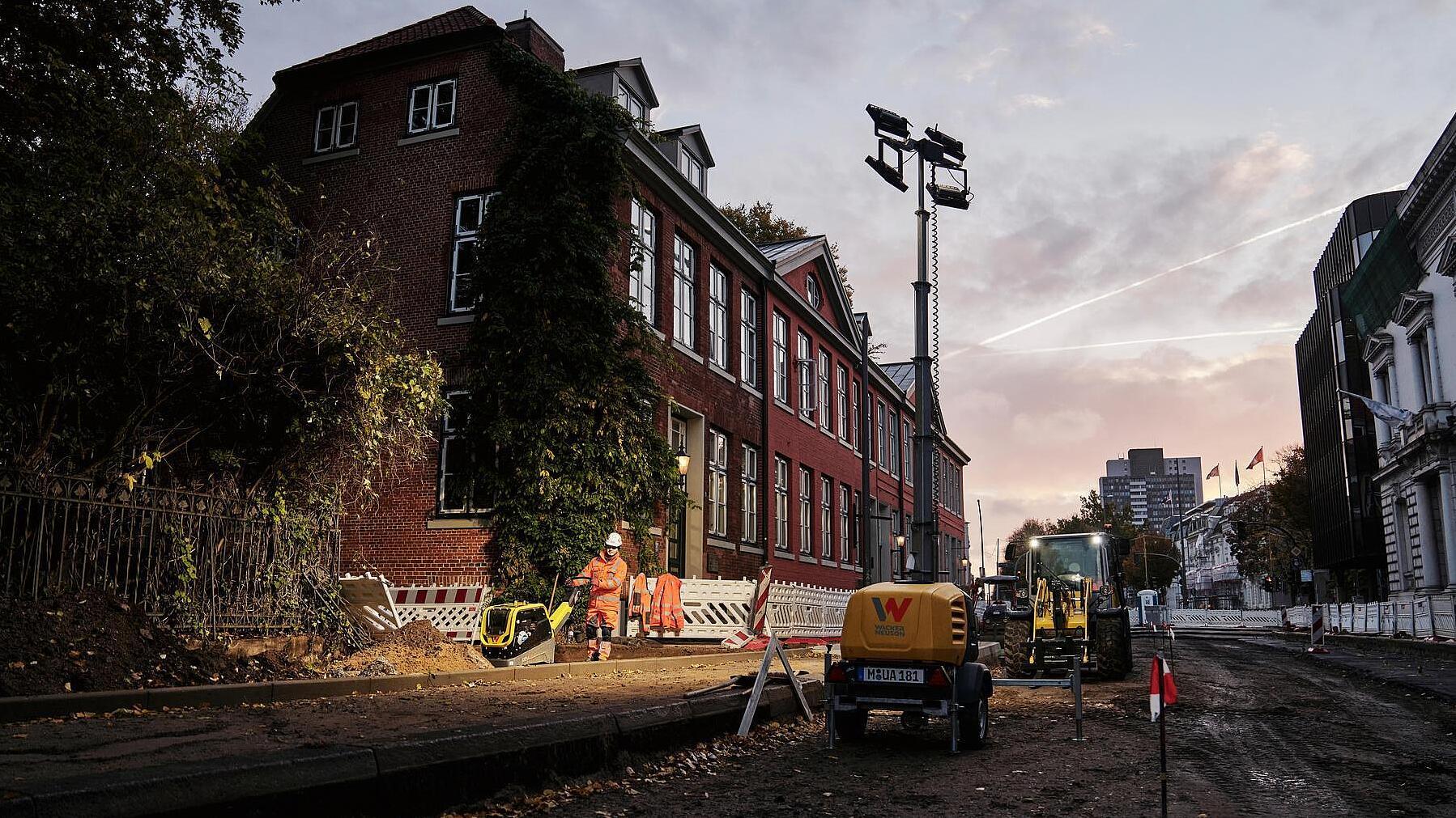 Construction site at dawn, worker working under light tower