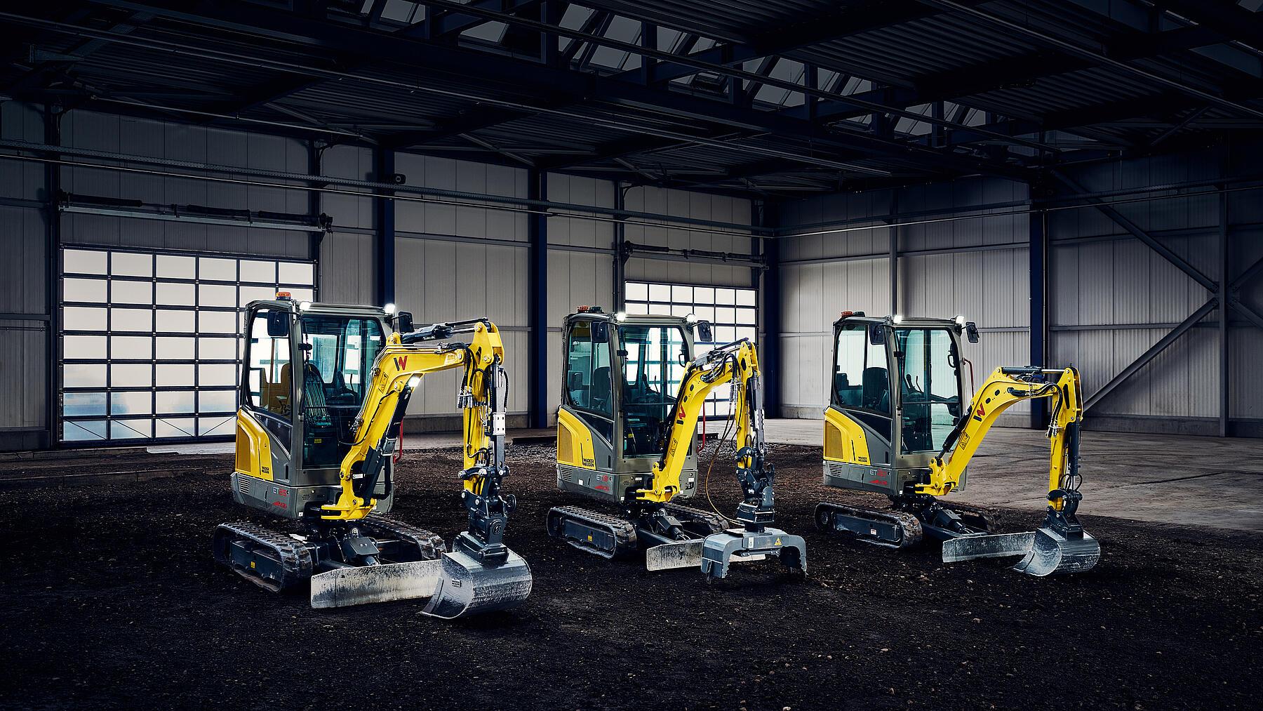 three yellow mini excavator in industry hall
