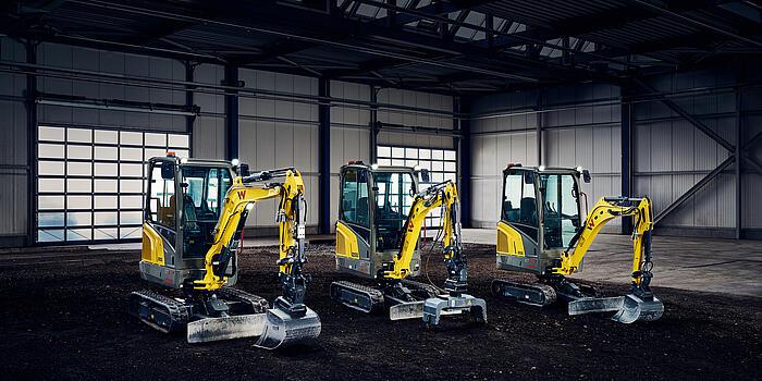 three yellow mini excavator in industry hall