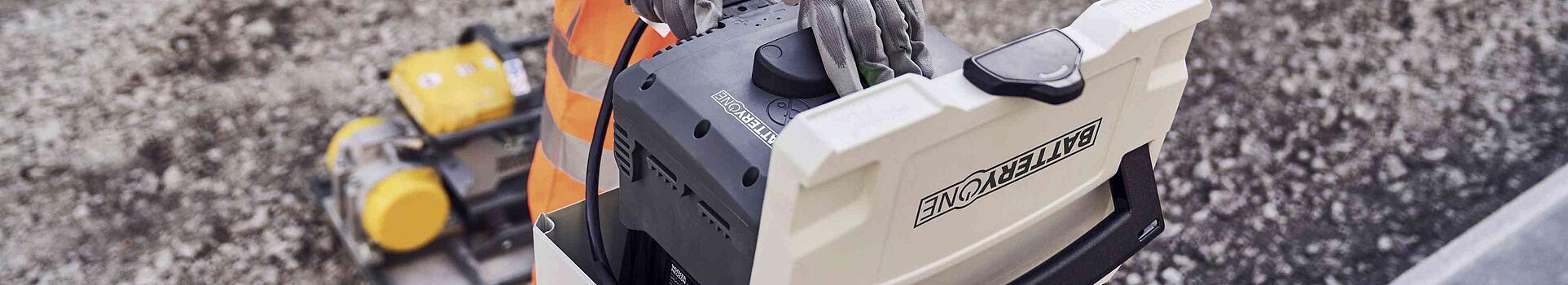 man charging battery at construction site