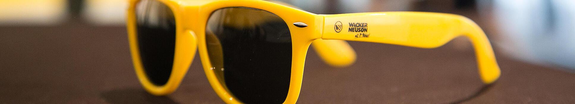 Gula solglasögon med Wacker Neusons logga.