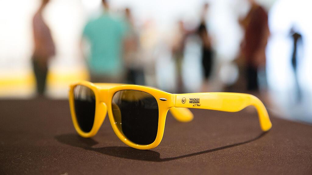 Yellow sunglasses with Wacker Neuson logo.