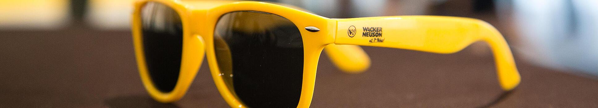 Gul solbrille med Wacker Neuson Logo.
