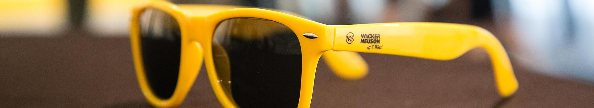 Des lunettes de soleil jaunes portant le logo Wacker Neuson.