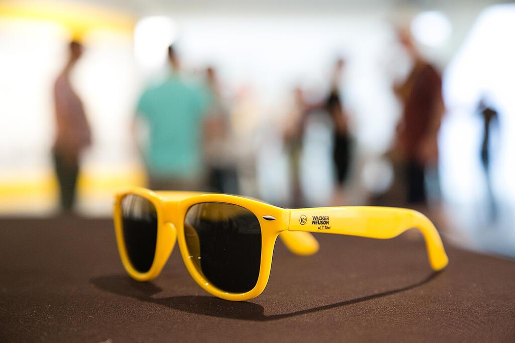 Yellow sunglasses with Wacker Neuson logo.