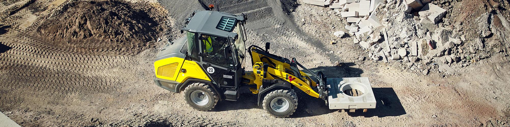 Wacker Neuson WL750p performance wheel loader transporting a concrete element on a construction site.