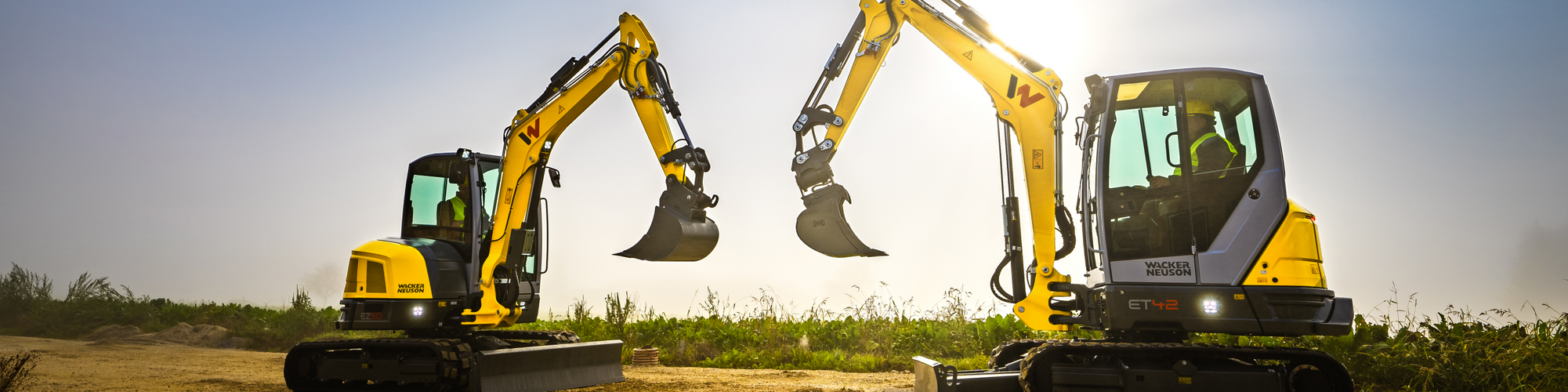 Two Wacker Neuson tracked excavators standing on a construction site.