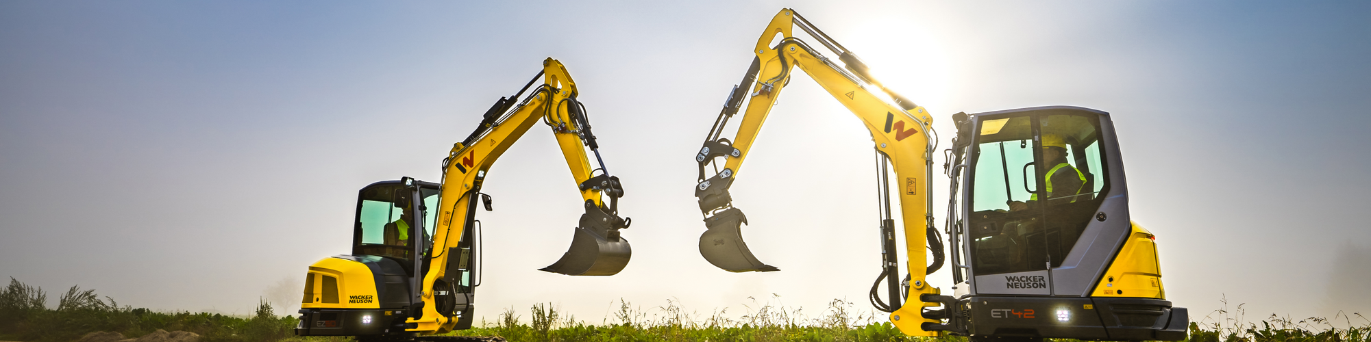 Two Wacker Neuson tracked excavators standing on a construction site.