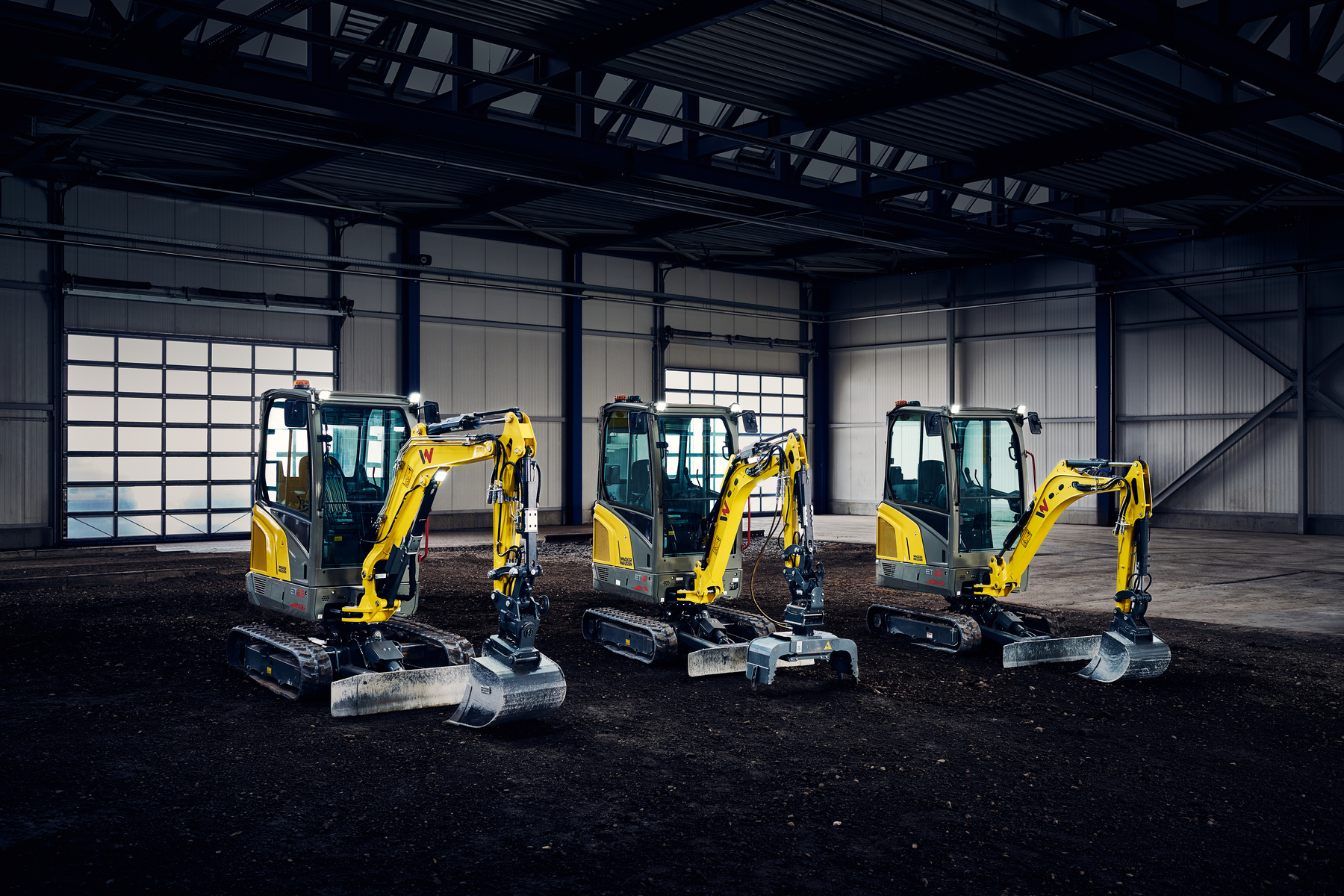 three yellow mini excavator in industry hall