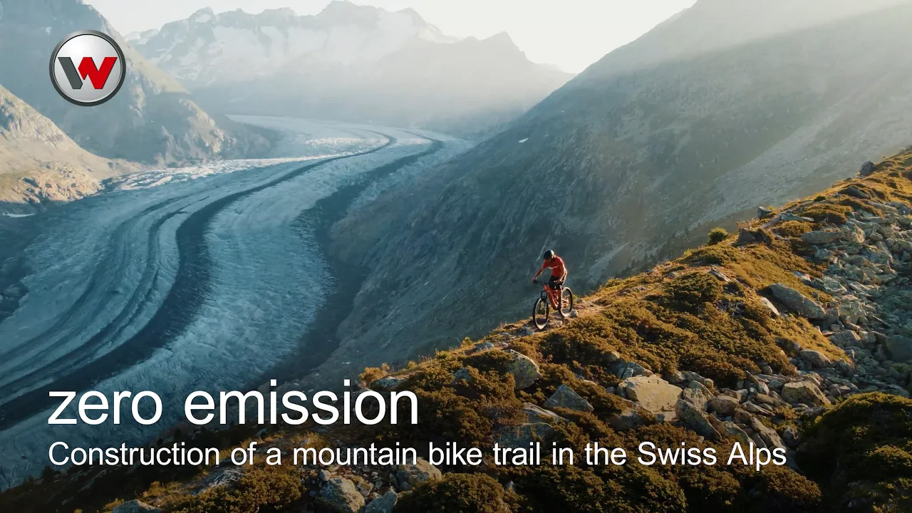 man riding a mountain bike on a mountain ridge with snowy mountains in the background